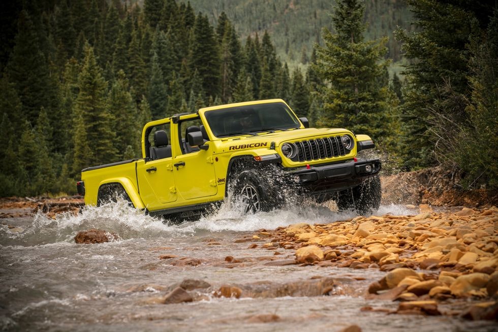 2024 Jeep Gladiator driving through a stream in the woods