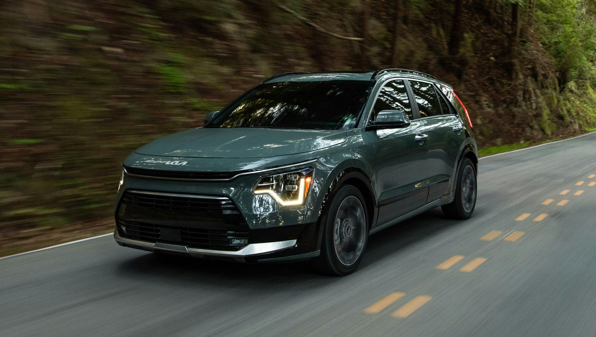 2024 Kia Niro driving down a wooded road