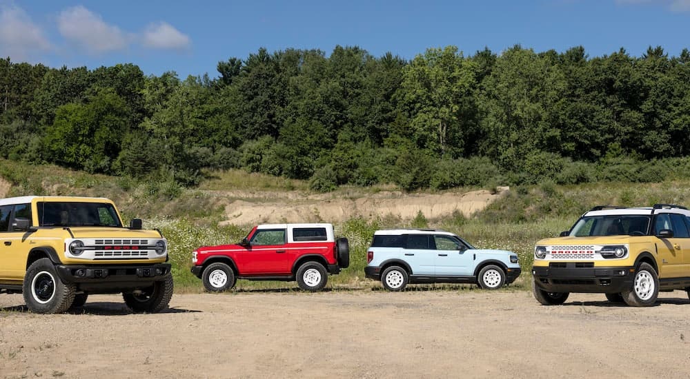 Two 2023 Ford Bronco Heritage editions and two 2023 Ford Bronco Sport Heritage editions are shown lined up off-road.