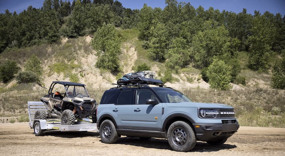 A blue 2024 Ford Bronco Sport Badlands is shown towing a UTV.