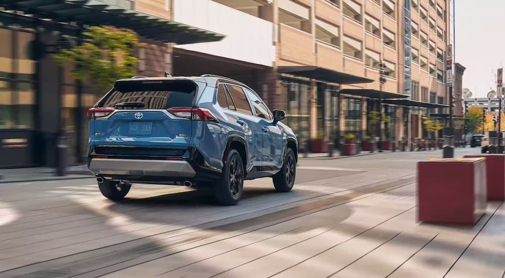 A blue 2022 Toyota RAV4 Prime is shown from the rear at an angle after leaving a dealer that has a used RAV4 for sale.