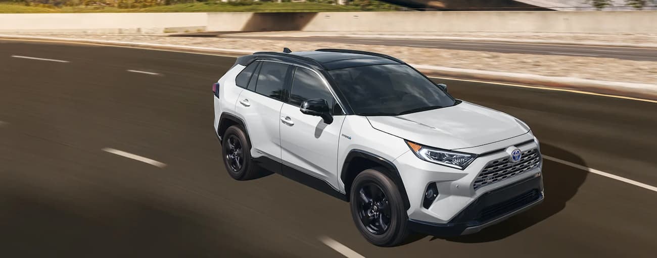 A white 2020 Toyota RAV4 Hybrid is shown on a highway after leaving a Springfield, VT Toyota dealer.