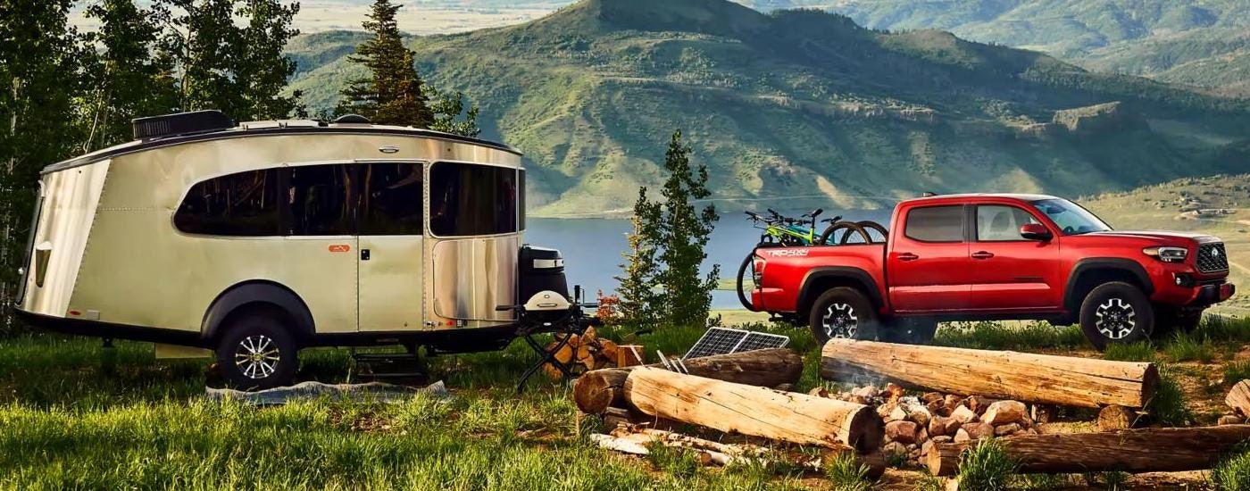 A red 2023 Toyota Tacoma is shown parked at a remote campsite with a mountain view.