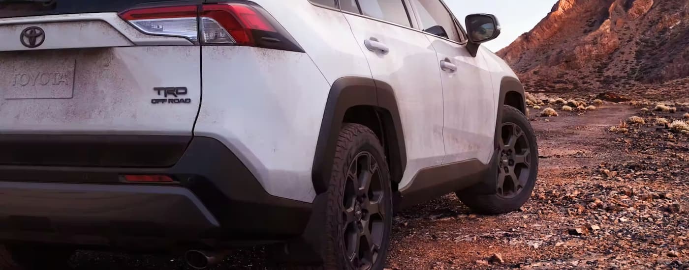 A white 2022 Toyota RAV4 TRD Off-Road is shown off-roading on a rocky path.
