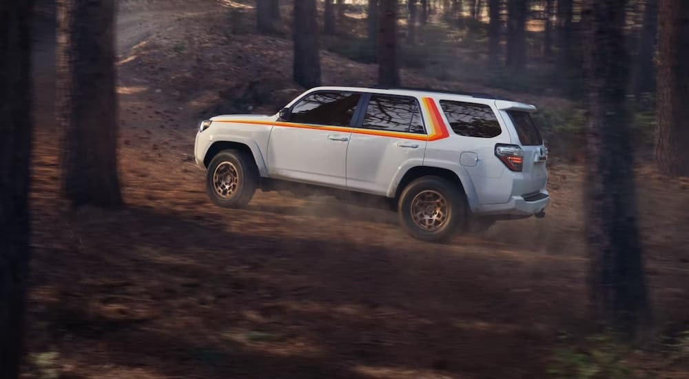 A white 2023 Toyota 4Runner Anniversary Edition is shown from the side while off-road.