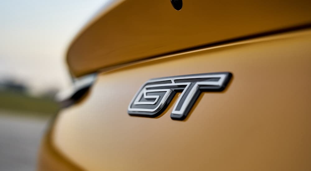 A close-up shows the rear badge of a yellow 2024 Ford Mustang Mach-E GT.