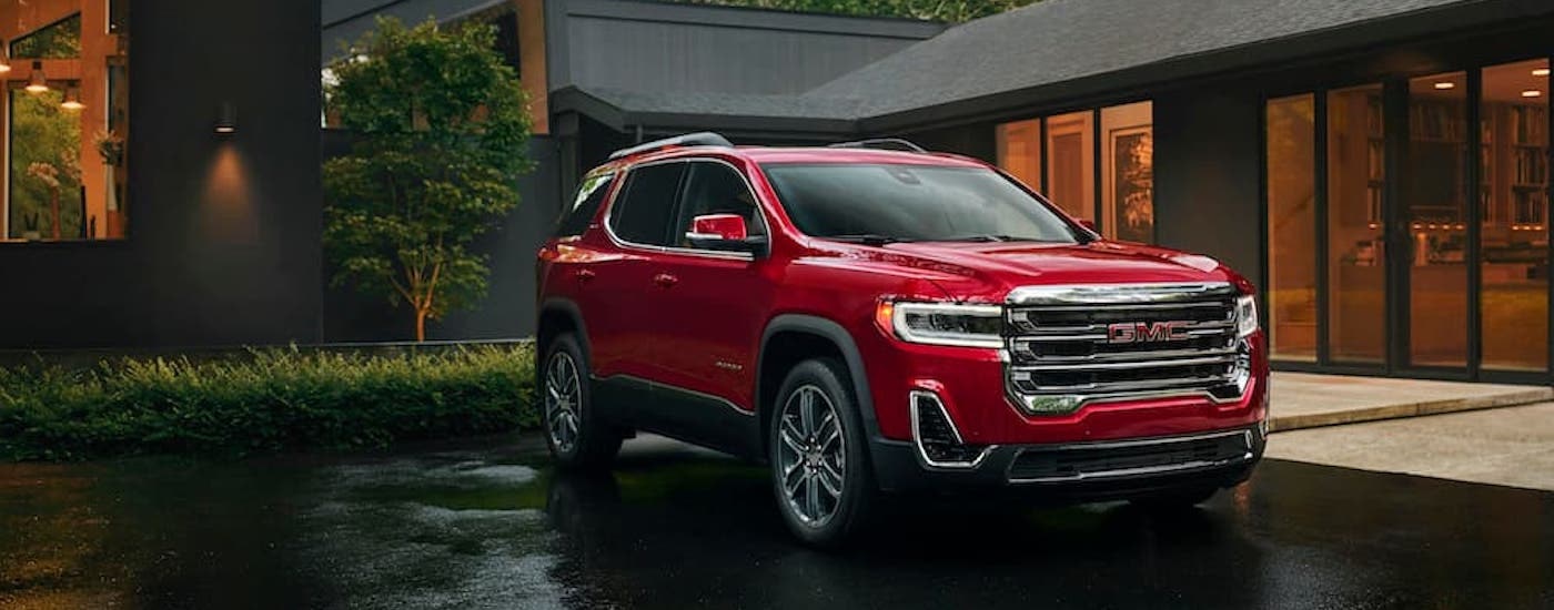 A red 2023 GMC Acadia is shown from the front at an angle after leaving a dealer that has used SUVs for sale.
