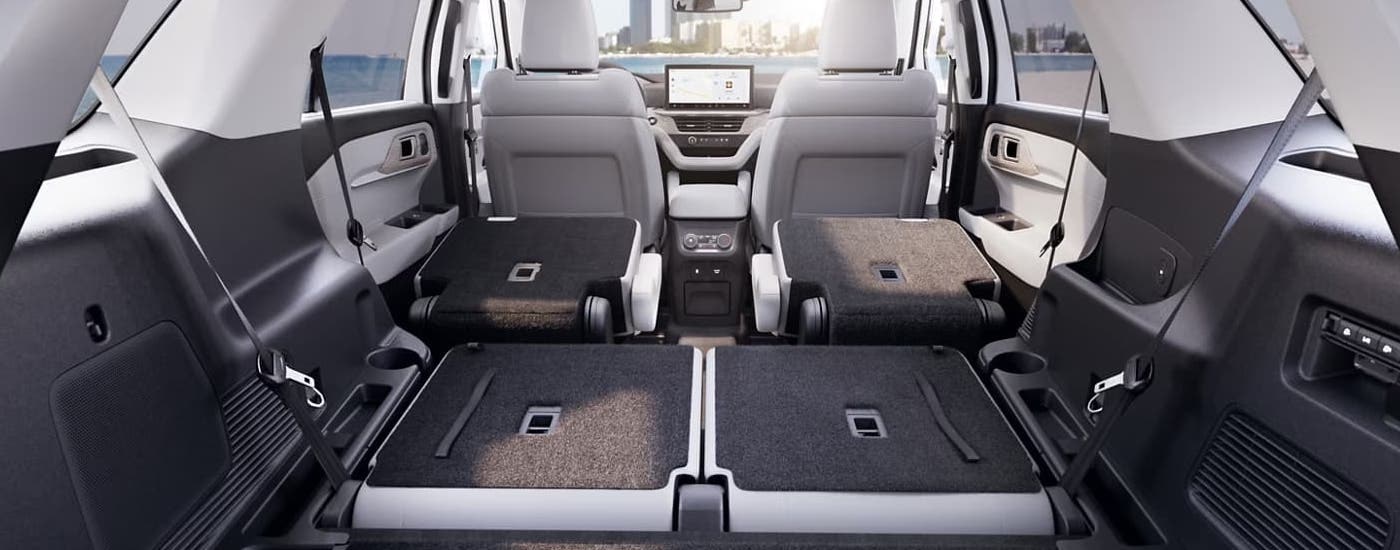 The black and light grey interior of a 2025 Ford Explorer shows the rear seating folded down.