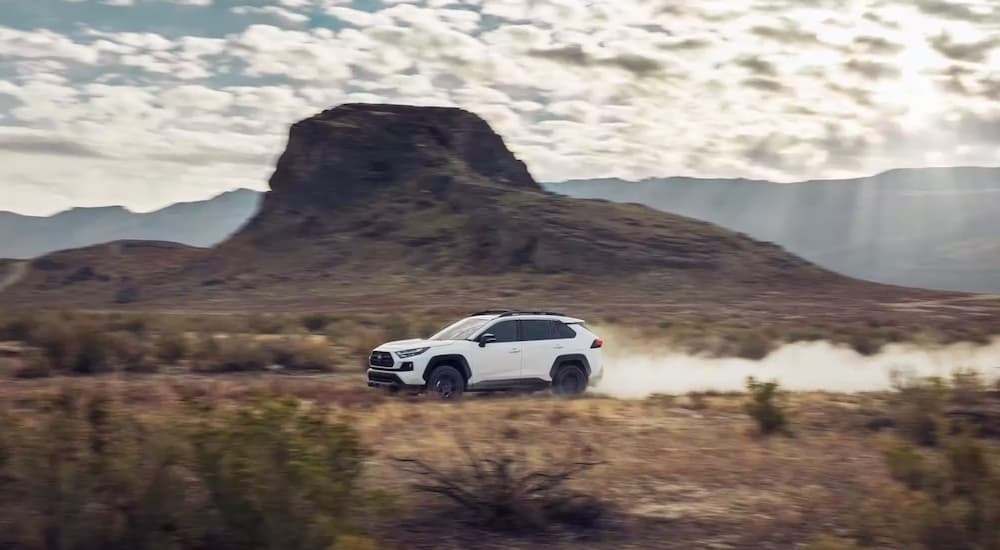 A white 2024 Toyota RAV4 TRD is shown from the side while off-road.