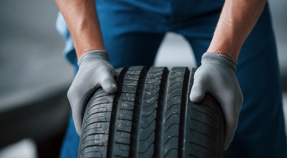 A mechanic is shown inspecting a tire at a dealer that has used cars for sale.
