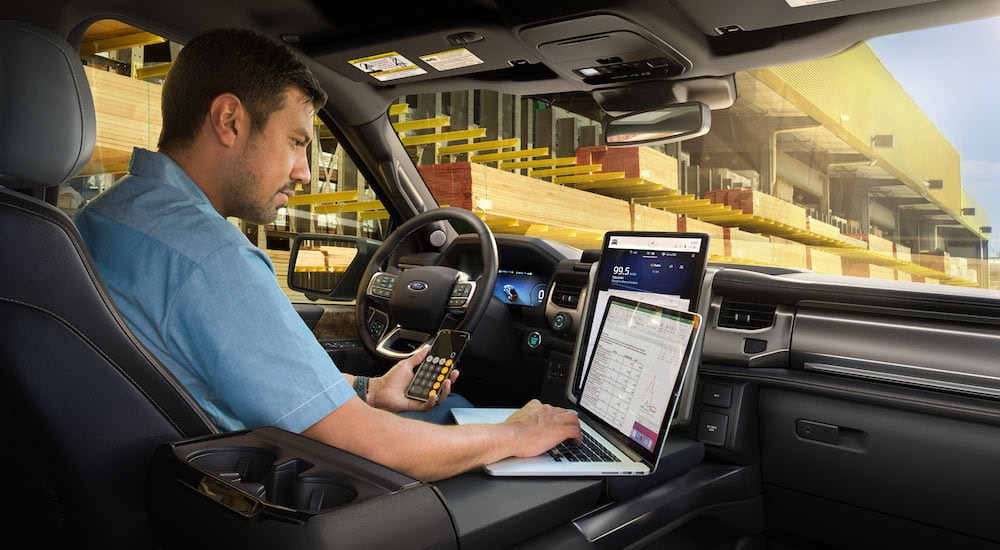 A man is shown working in the front seat of a 2022 Ford F-150 Lightning.