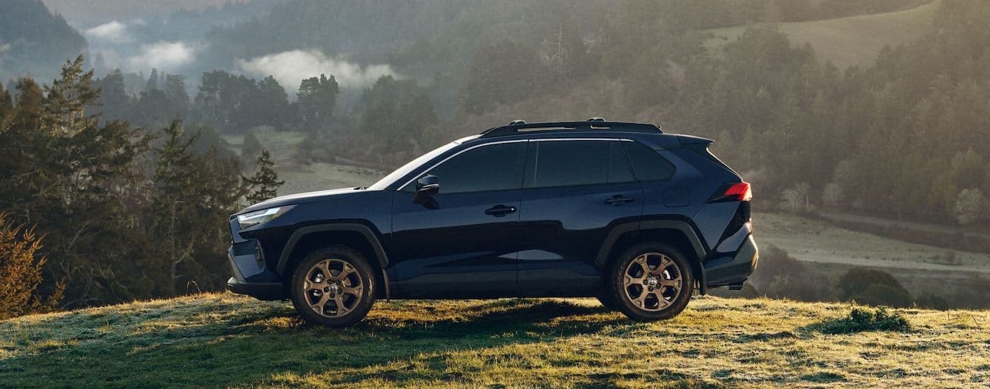 A blue 2023 Toyota RAV4 is shown from the side while off-road.