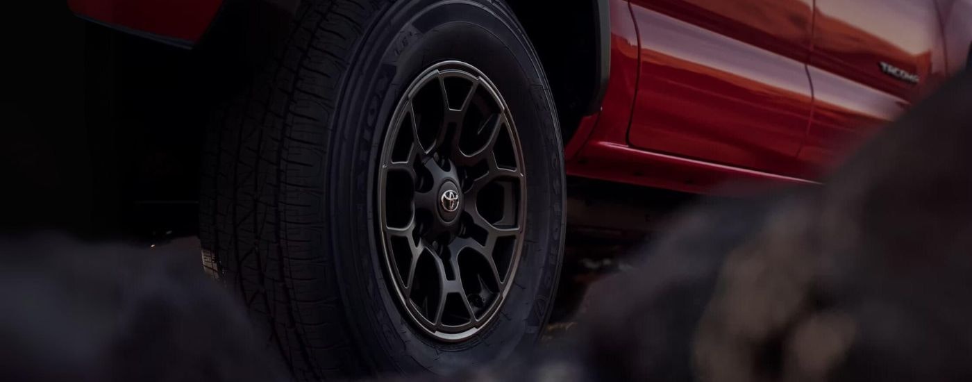 A close up shows the black wheel on a red 2023 Toyota Tacoma SR5 SX.