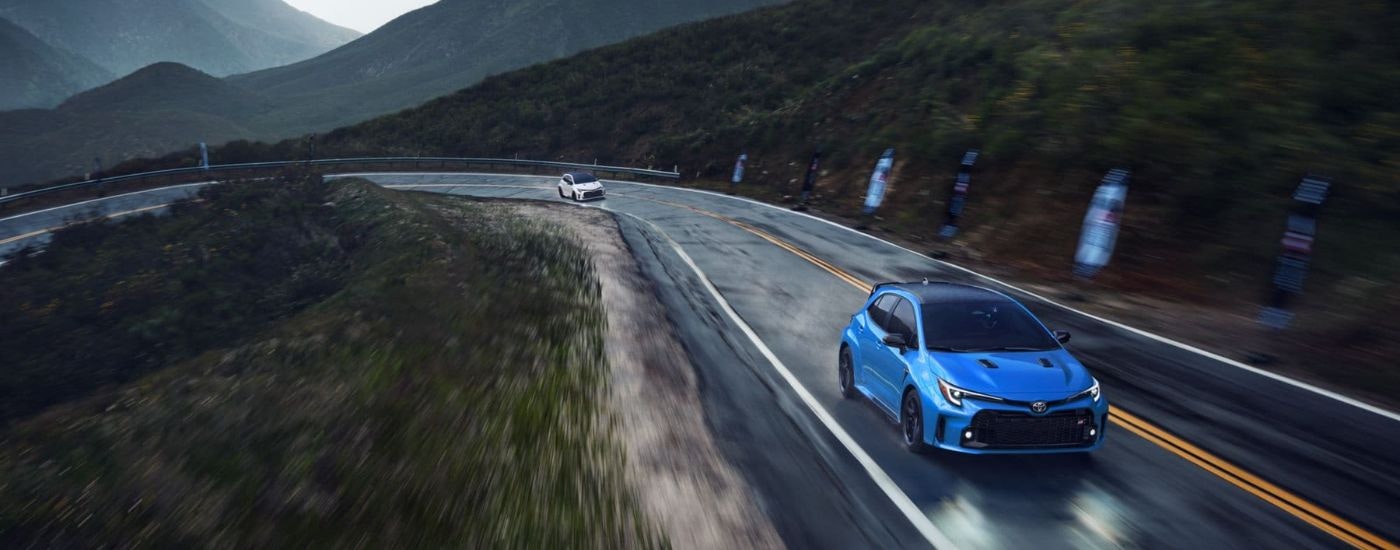 A blue 2024 Toyota GR Corolla Circuit Edition is shown on a mountain road after visiting a Toyota dealer near Keene.