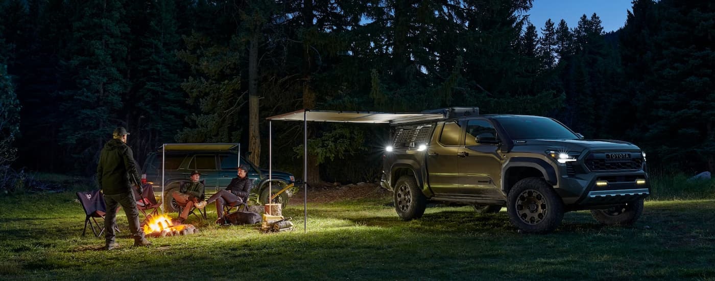 A black 2024 Toyota Tacoma Trailhunter is parked at night at a campsite.