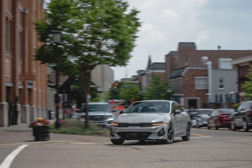 2024 Kia K5 driving through a town