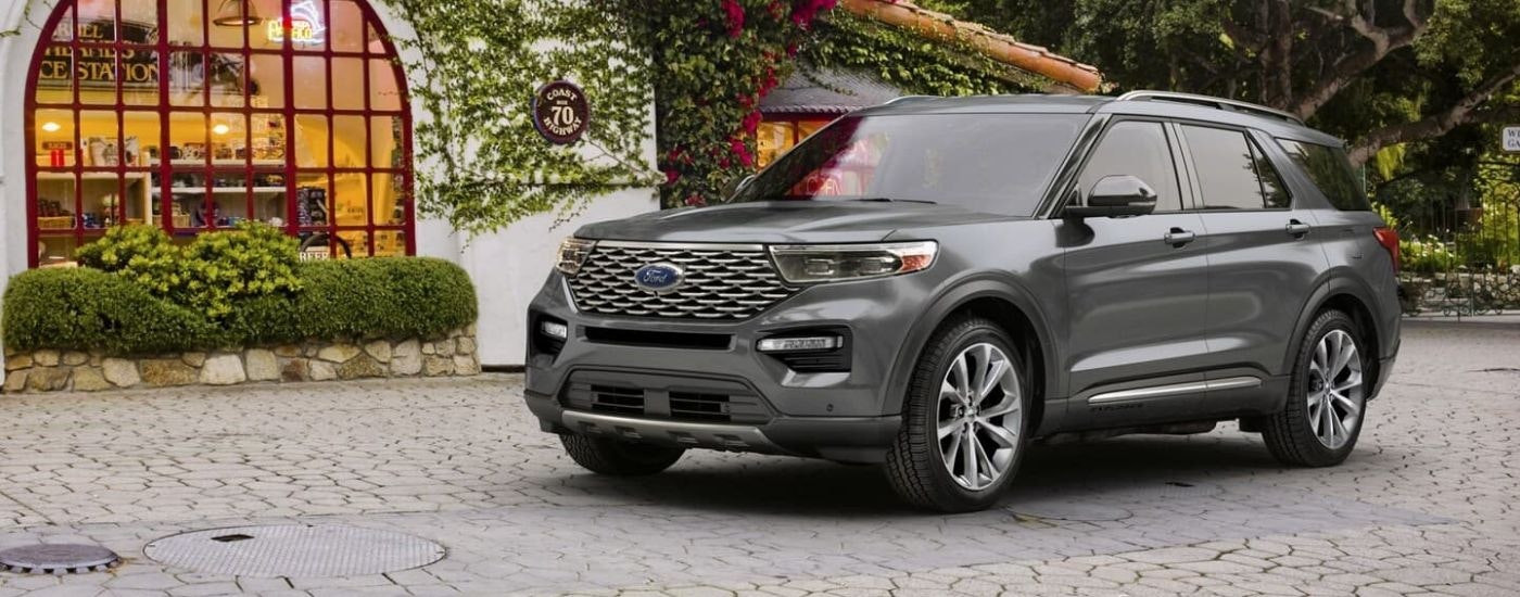 A grey 2024 Ford Explorer is shown parked in front of a shop.