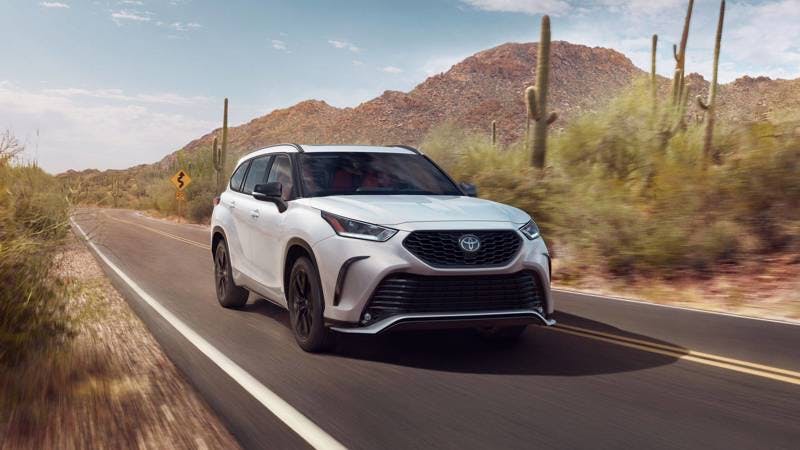 Highlander The 2024 Toyota Highlander driving down a road in the desert