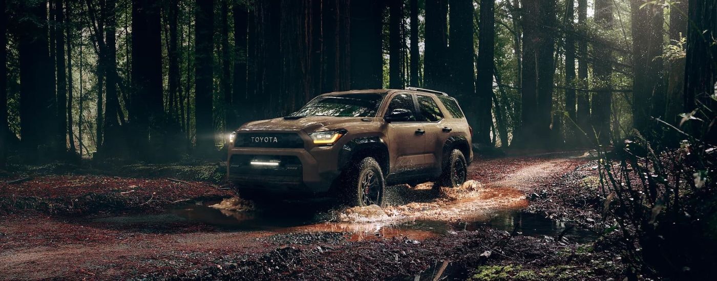 A brown 2025 Toyota 4Runner TRD Pro is shown driving through mud.