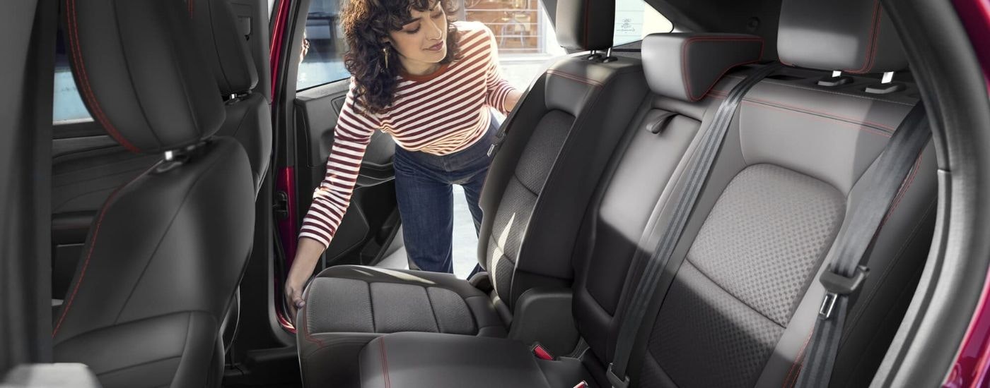 A person is shown adjusting a rear leather set in a red 2025 Ford Escape.