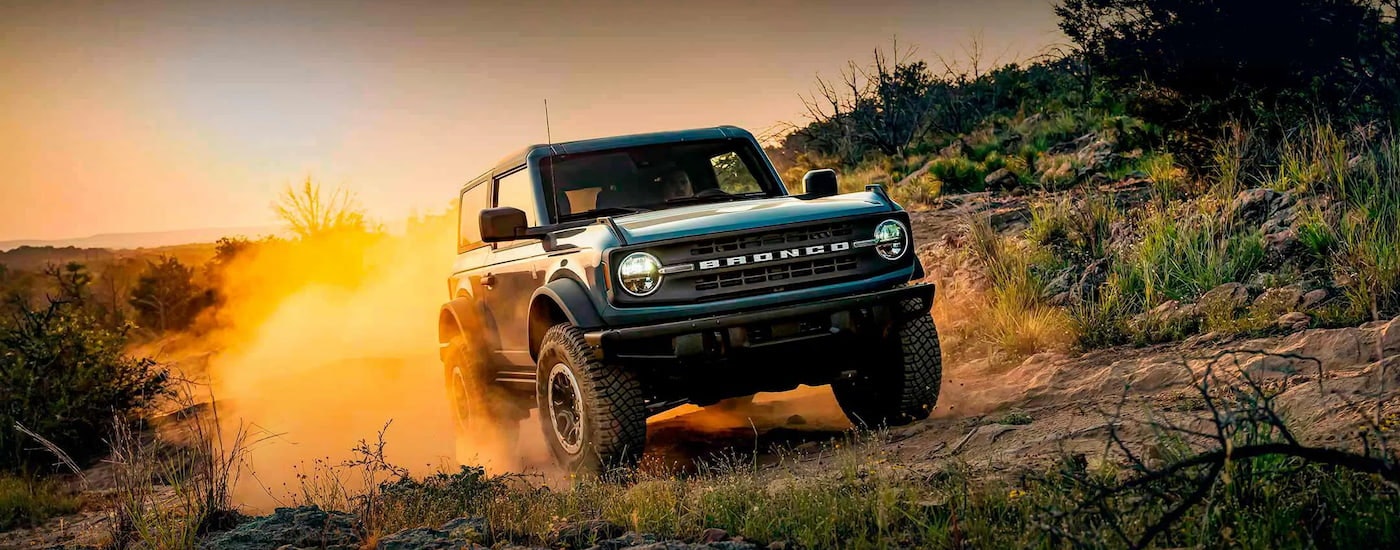 A teal 2024 Ford Bronco Black Diamond off-roading on a dusty trail.