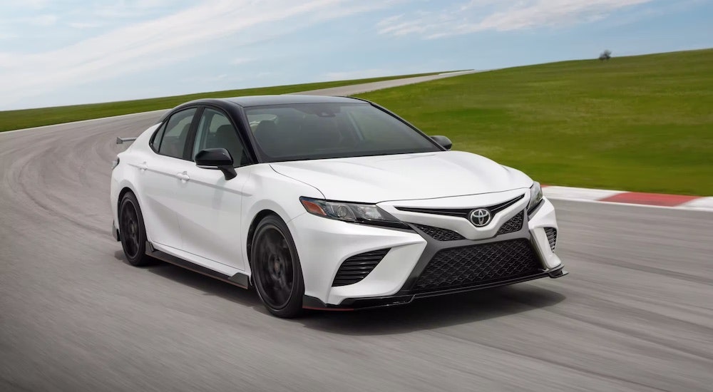 A white 2023 Toyota Camry TRD is shown from the front at an angle after leaving a dealer that has a used Toyota for sale.