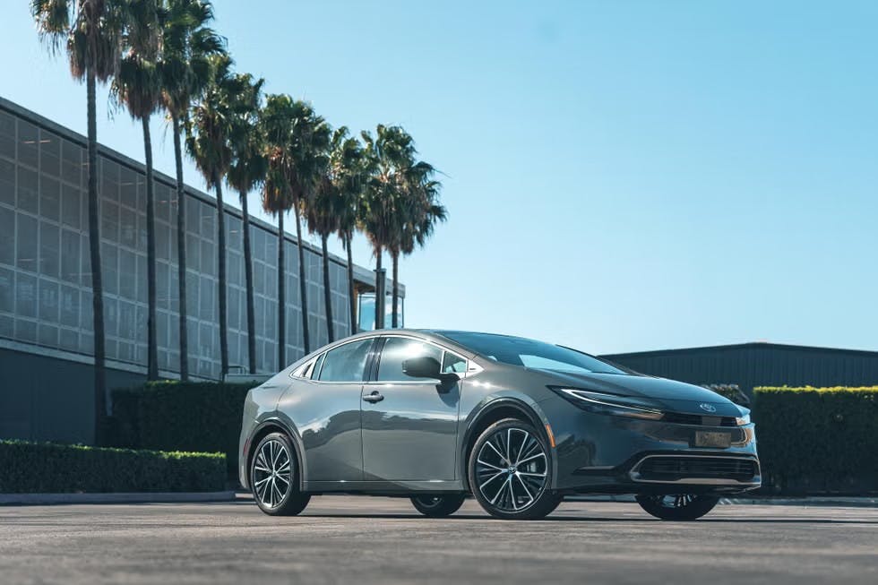z57oxrxa 2025 Toyota Prius parked outside of a building with palm trees