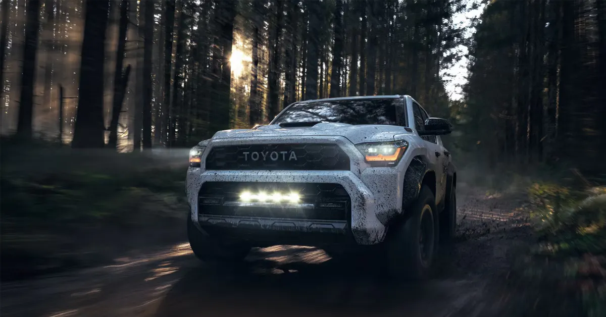 A 2026 Toyota 4Runner drives through a muddy forest trail