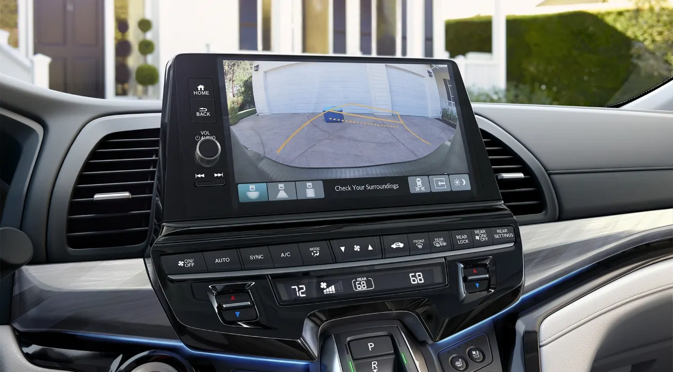 Honda infotainment touchscreen displaying the rearview camera image with parking guidelines and surrounding safety indicators.