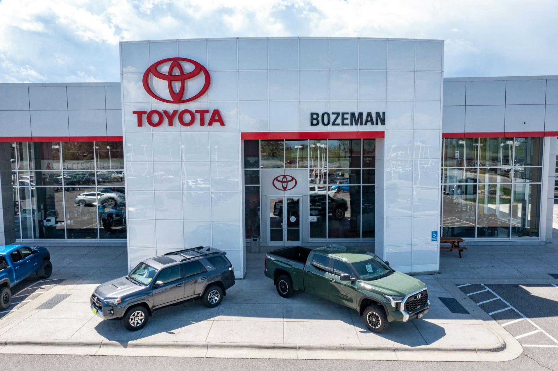 green 2024 Tacoma and grey 4Runner parked in front of Toyota of Bozeman in Montana