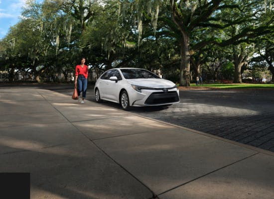 woman walking beside white toyota