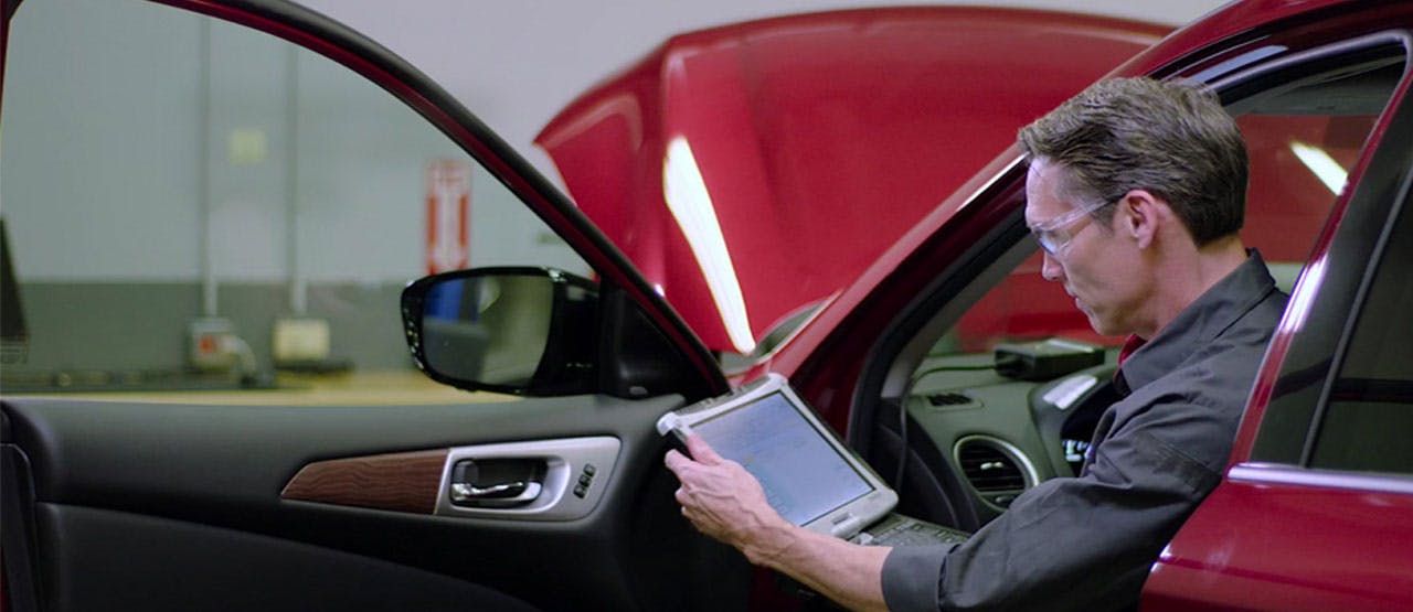 male service tech sitting in driver seat reading tablet
