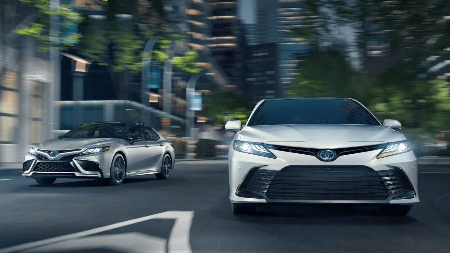 Two Camry Hybrid 2023 models driving.