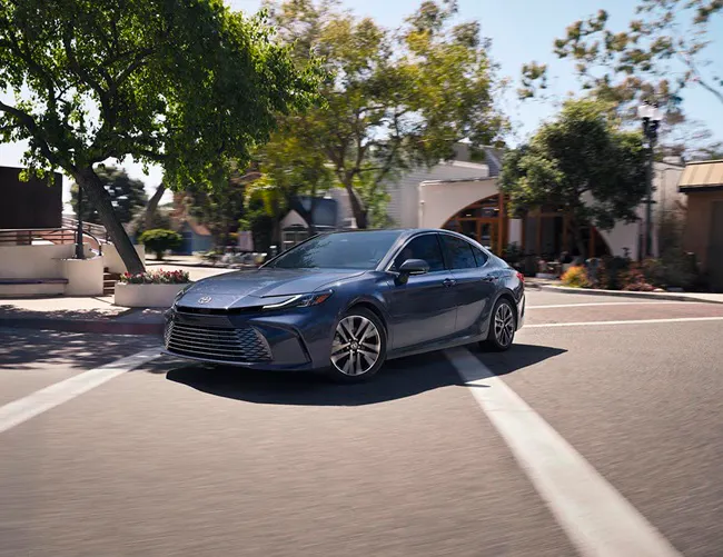 A Blue 2026 Toyota Camry turns a corner at a intersection.