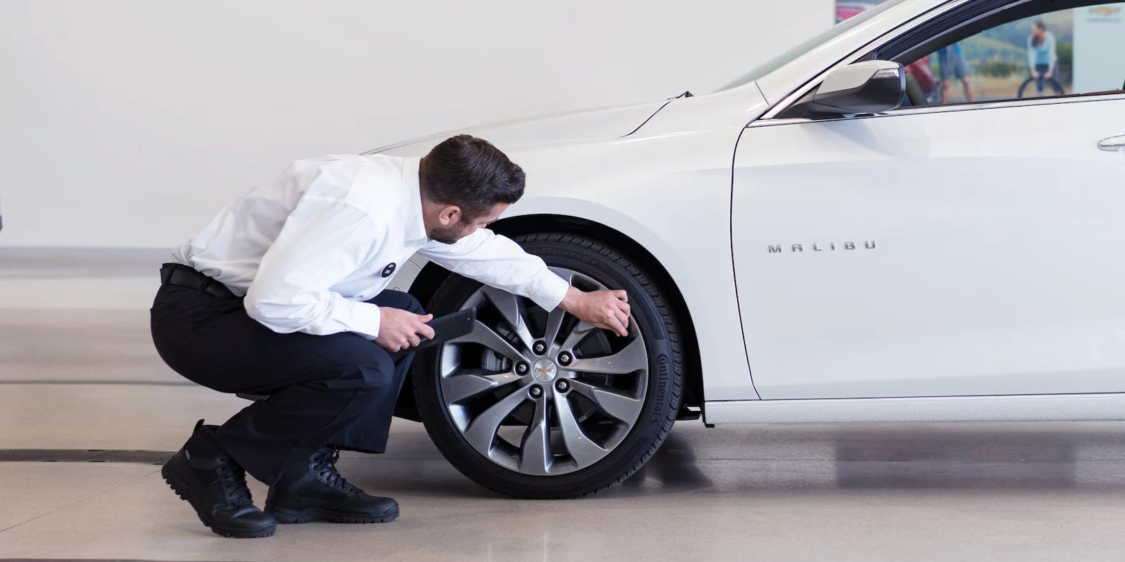male employee check tires white sedan