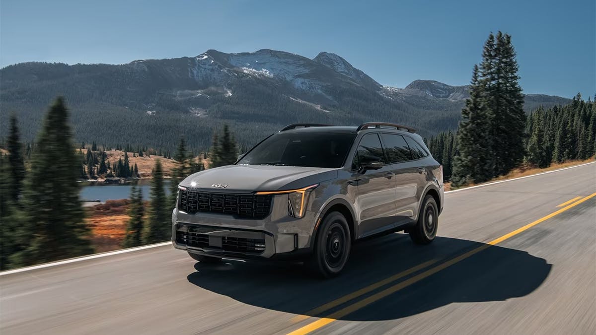 2024 Kia Sorento driving down a road by the mountains