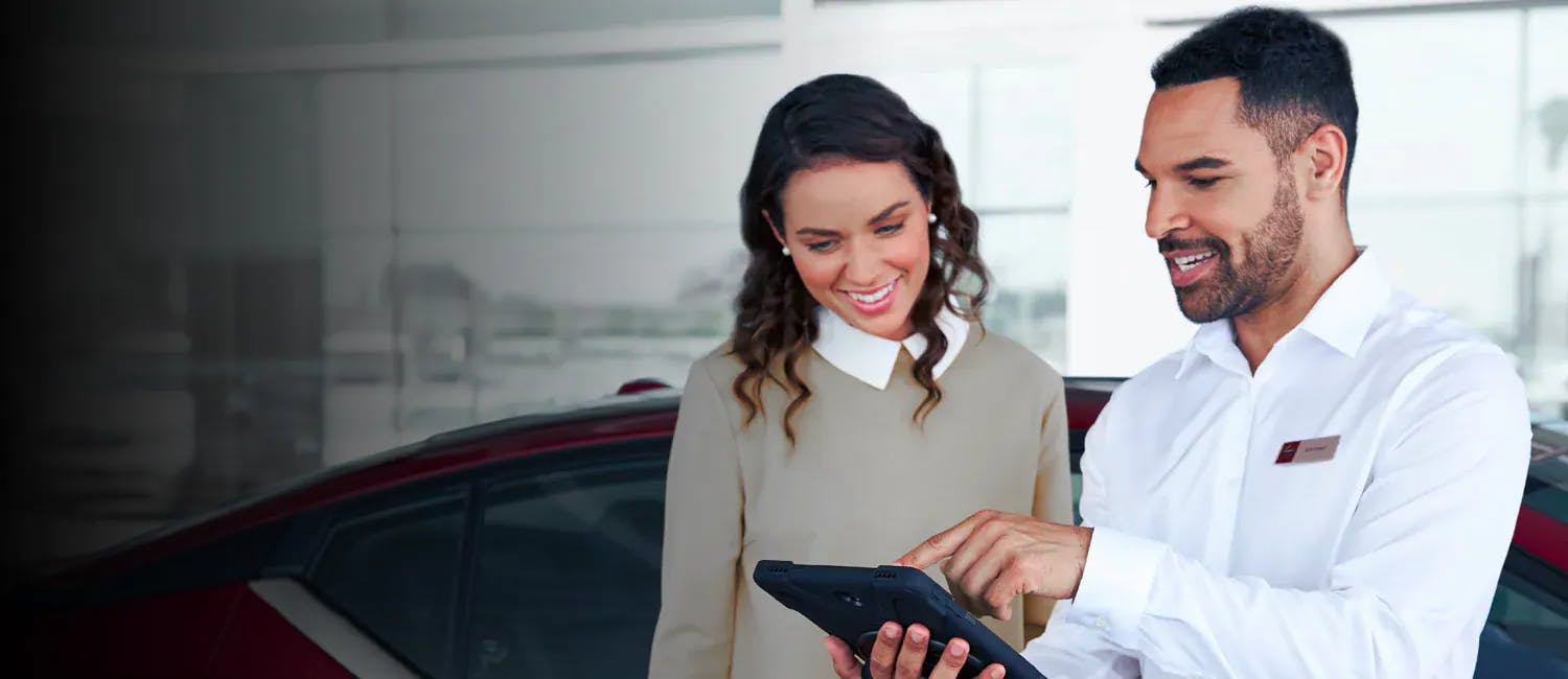 A sales consultant explains something on a mobile tablet to a customer