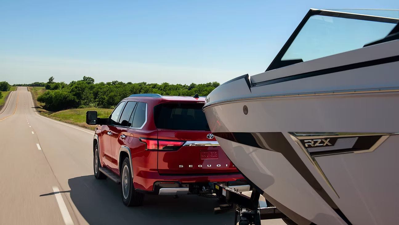 Red 2023 Toyota Sequoia towing a boat.