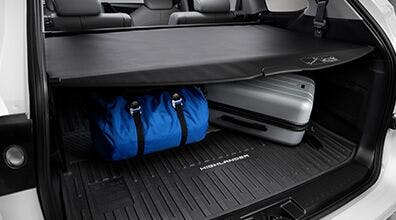 Cargo mat with blue bag and silver suitcase.