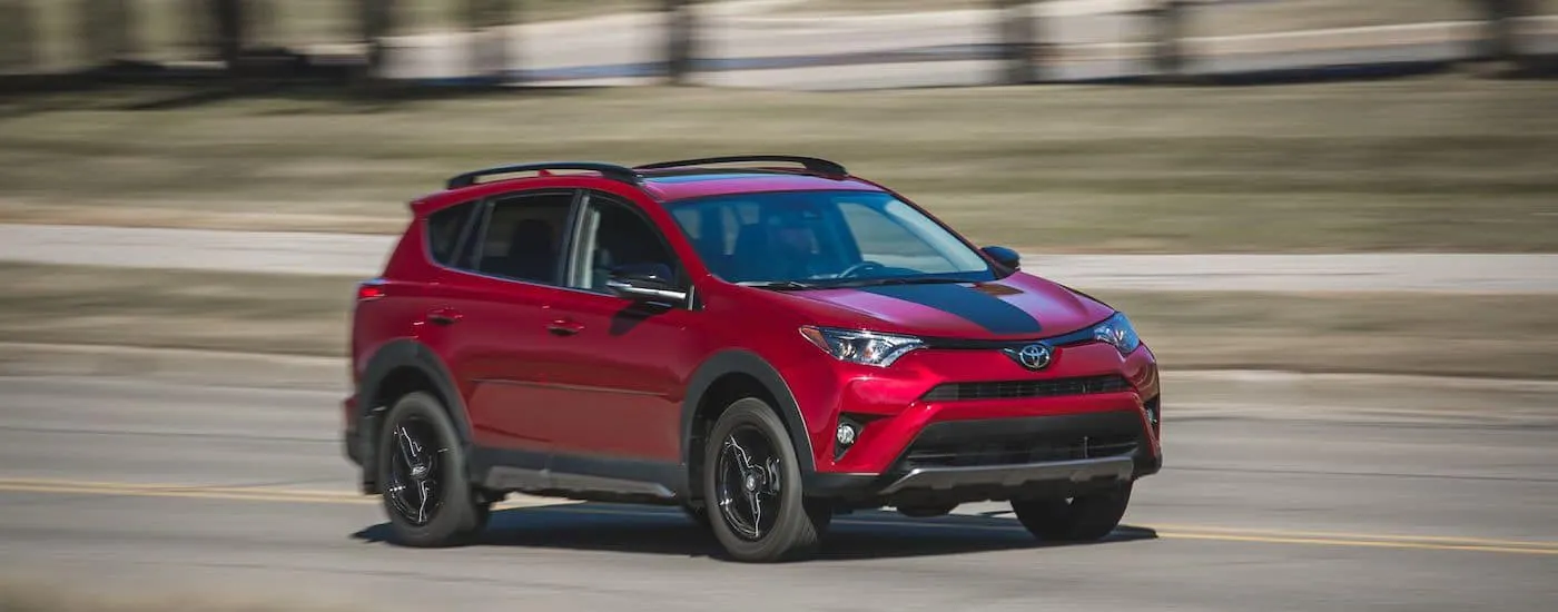Red 2018 Toyota RAV4 driving down an open road.