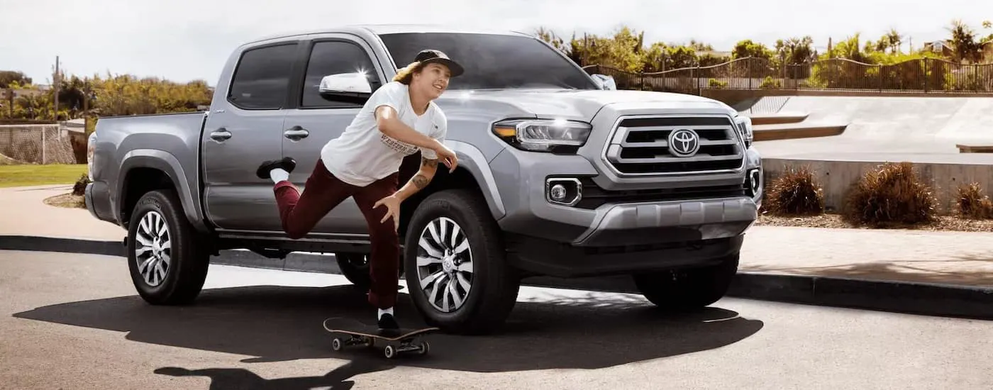 A person riding a skateboard by a white 2022 Toyota Tacoma Limited.