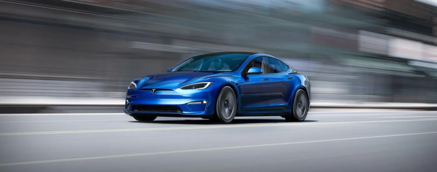 Blue 2023 Tesla Model S driving down a road.