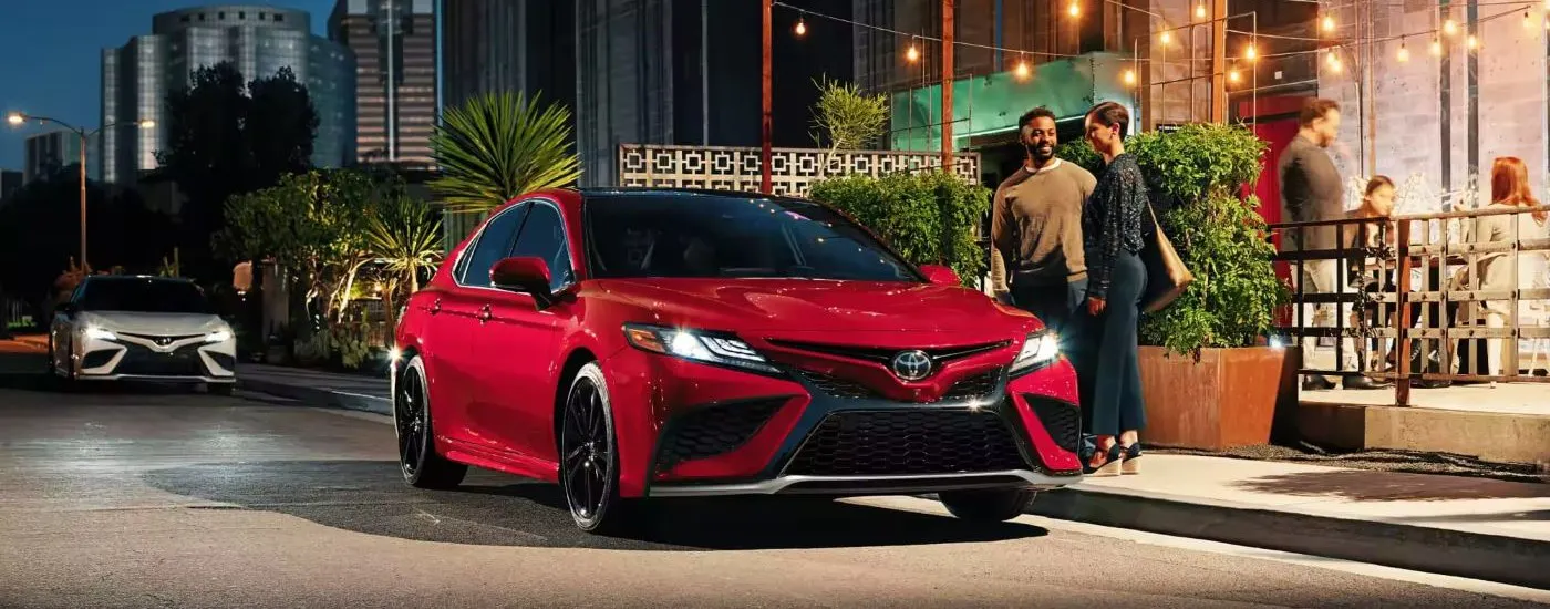 Red 2023 Toyota Camry parked by a city curb with a front angle view