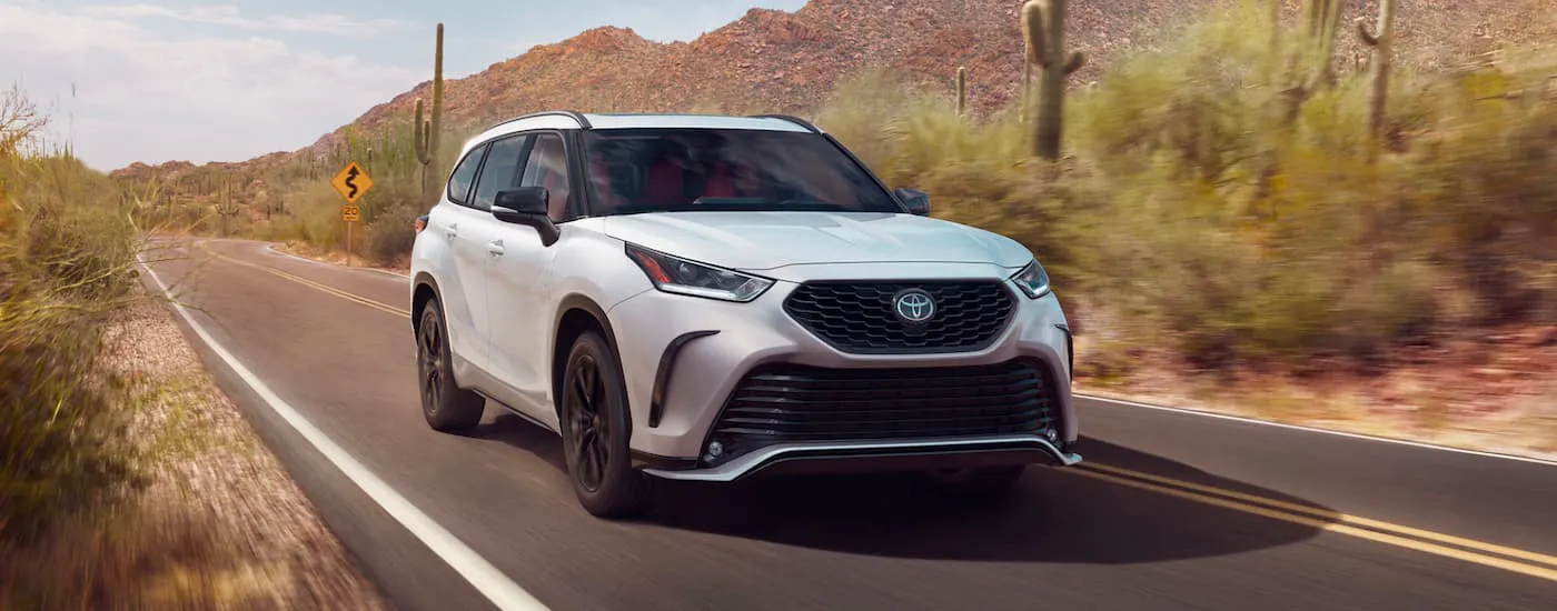 White 2023 Toyota Highlander XSE driving down an open road.