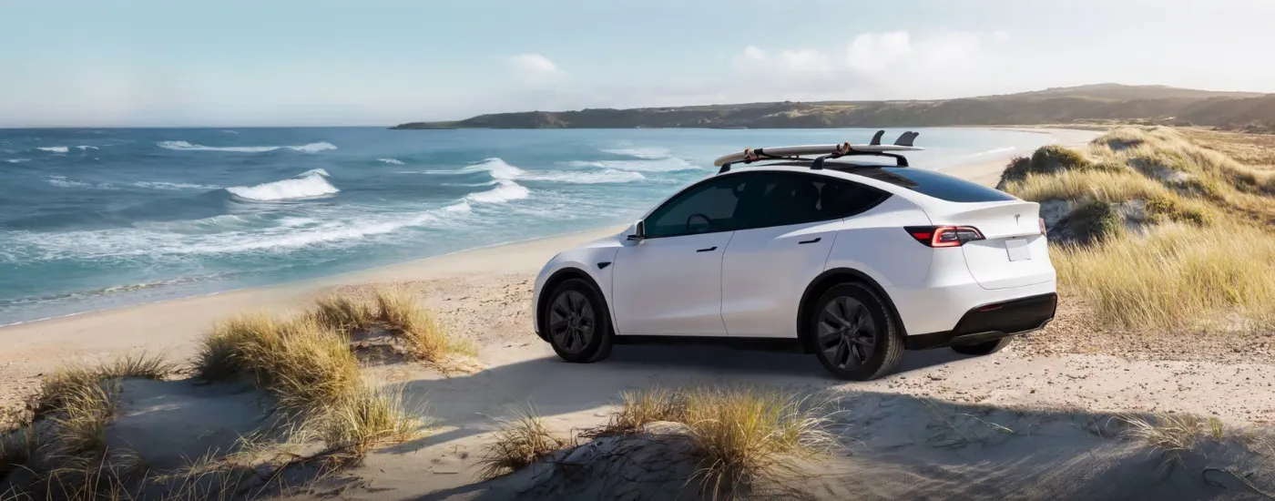 Rear of a white 2024 Tesla Model Y parked near water.
