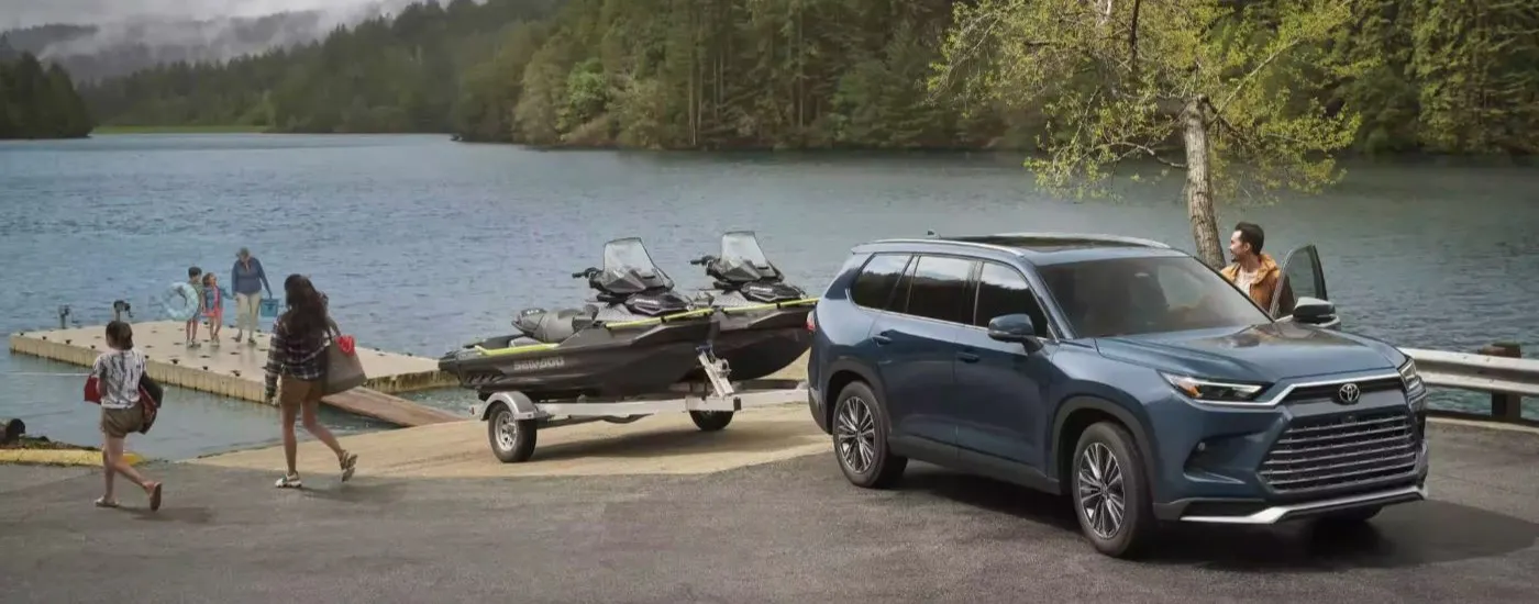 Blue 2026 Toyota Grand Highlander backing two jet skis into a lake