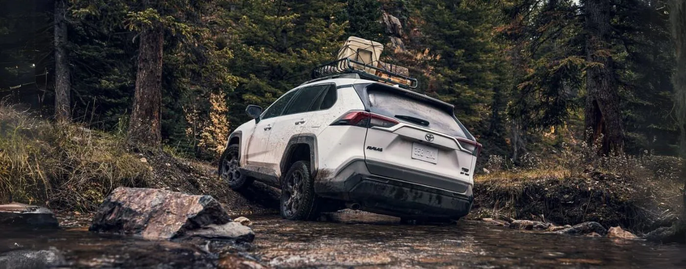 Rear view of a white 2024 Toyota Rav4 TRD driving off-road.