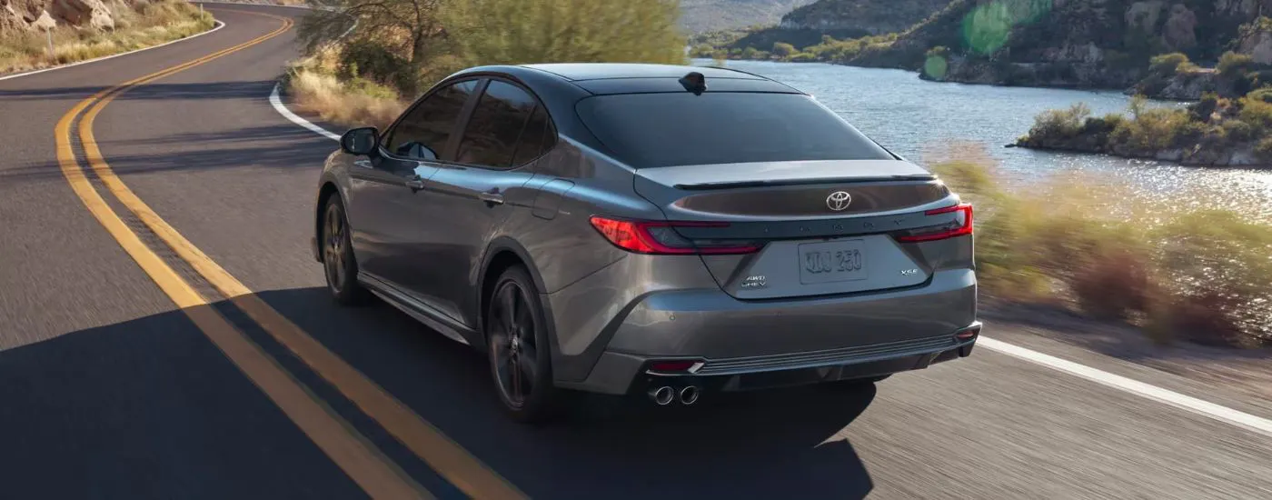 Blue 2025 Toyota Camry SE driving along a river