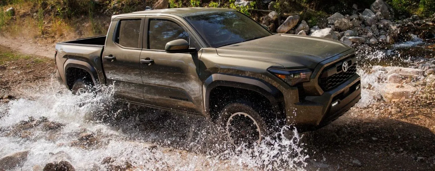 Grey 2025 Toyota Tacoma TRD Off-Road driving through a creek