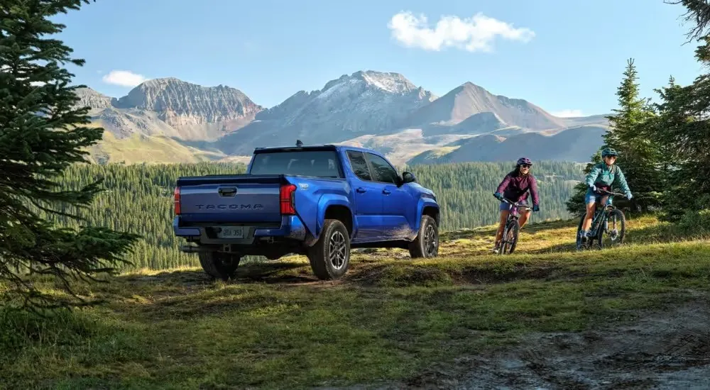 Blue 2026 Toyota Tacoma parked off-road with a biker going by